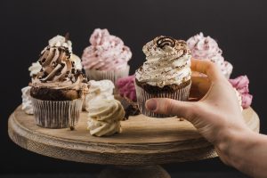 person-s-hand-selecting-cupcake-cake-stand